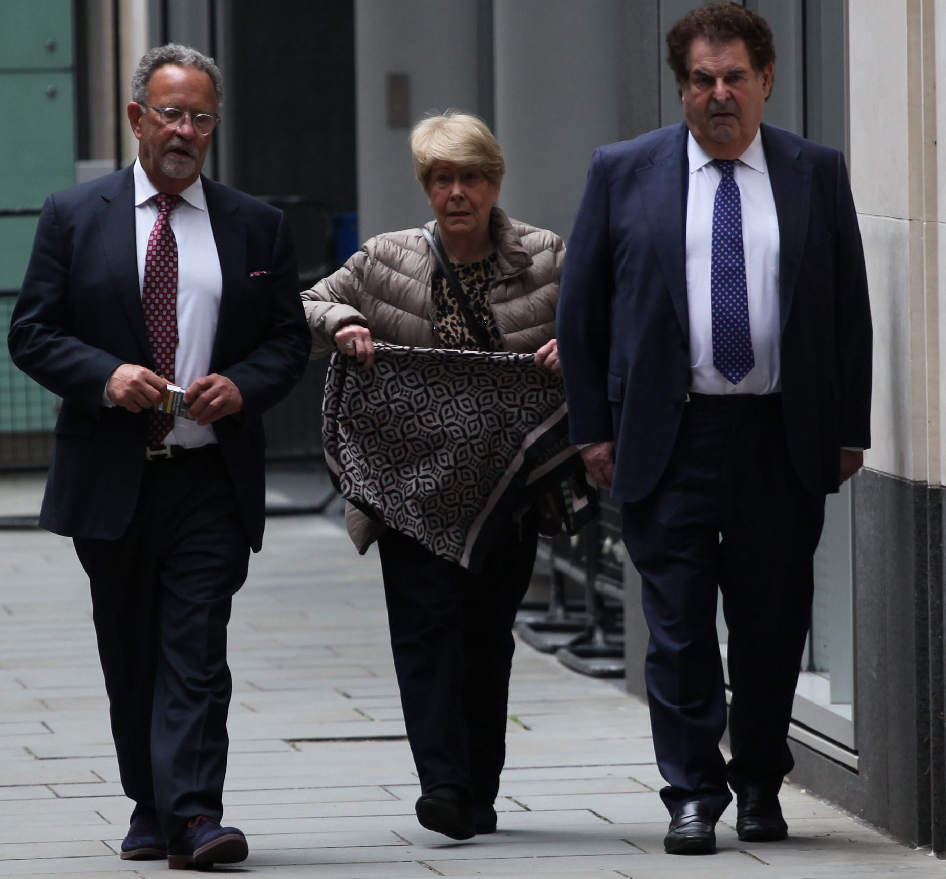 Three people walking outside the High Court.
