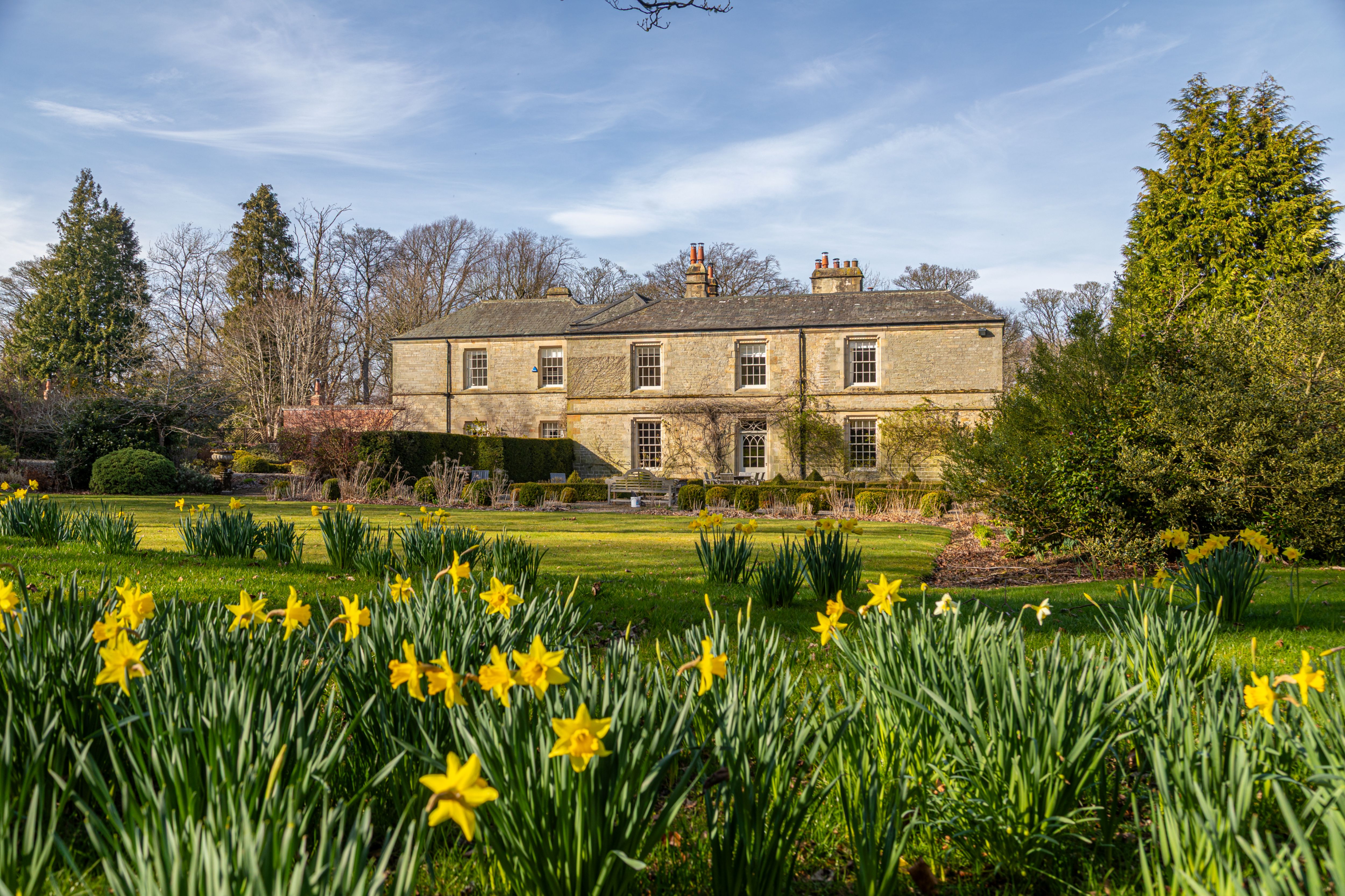 Broomshields Hall, a Grade II listed Georgian hall, surrounded by daffodils and landscaped gardens.