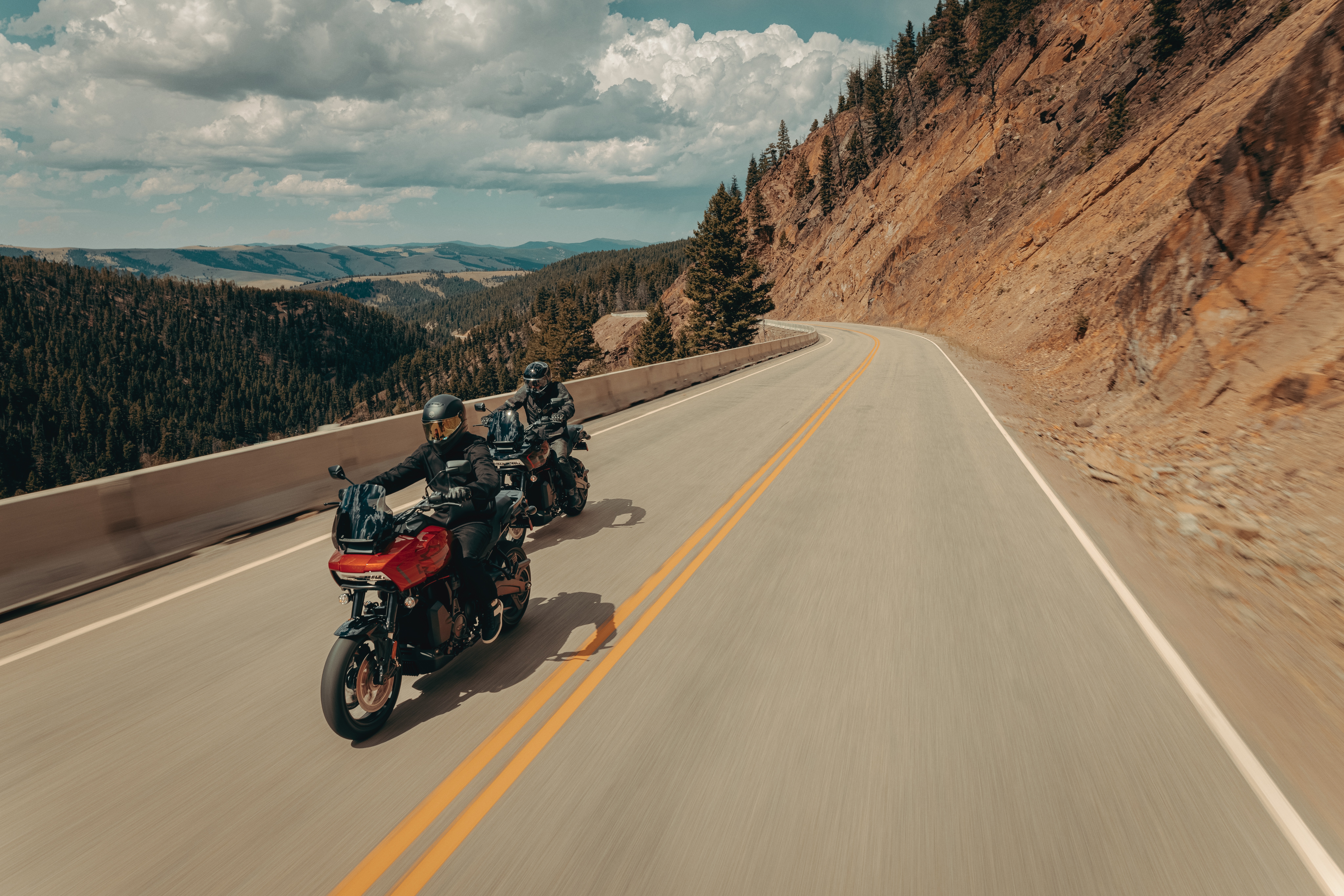 Two motorcyclists riding on a winding mountain road.