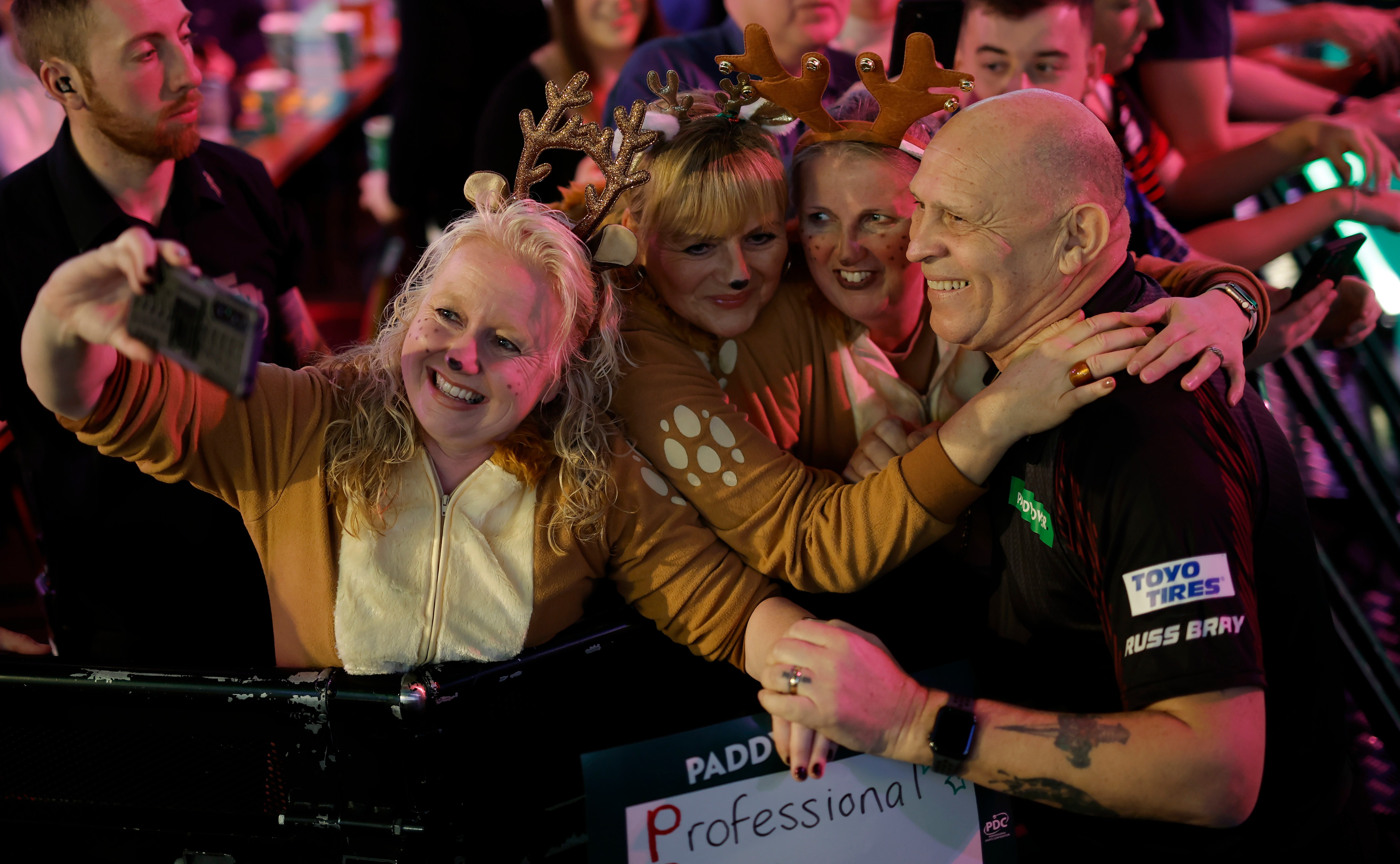 Russ Bray taking a selfie with three women dressed as reindeer at the PDC World Darts Championship.
